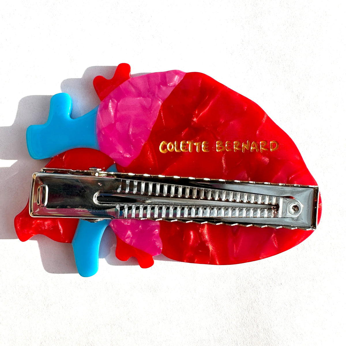 The back of the anatomical heart hair clip, showing the metal alligator clip mechanism and the engraved "colette bernard" logo