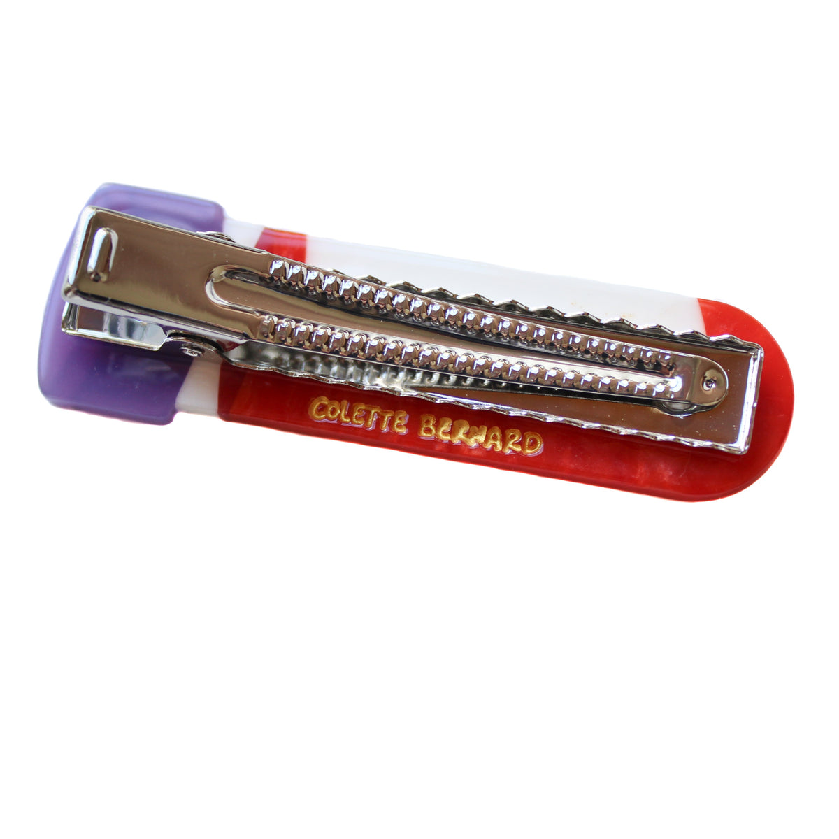 a hair clips designed to look like a blood vial. The clip is red with a white sample label, and a purple cap. the clip is upside down, showing the alligator clip mechanism