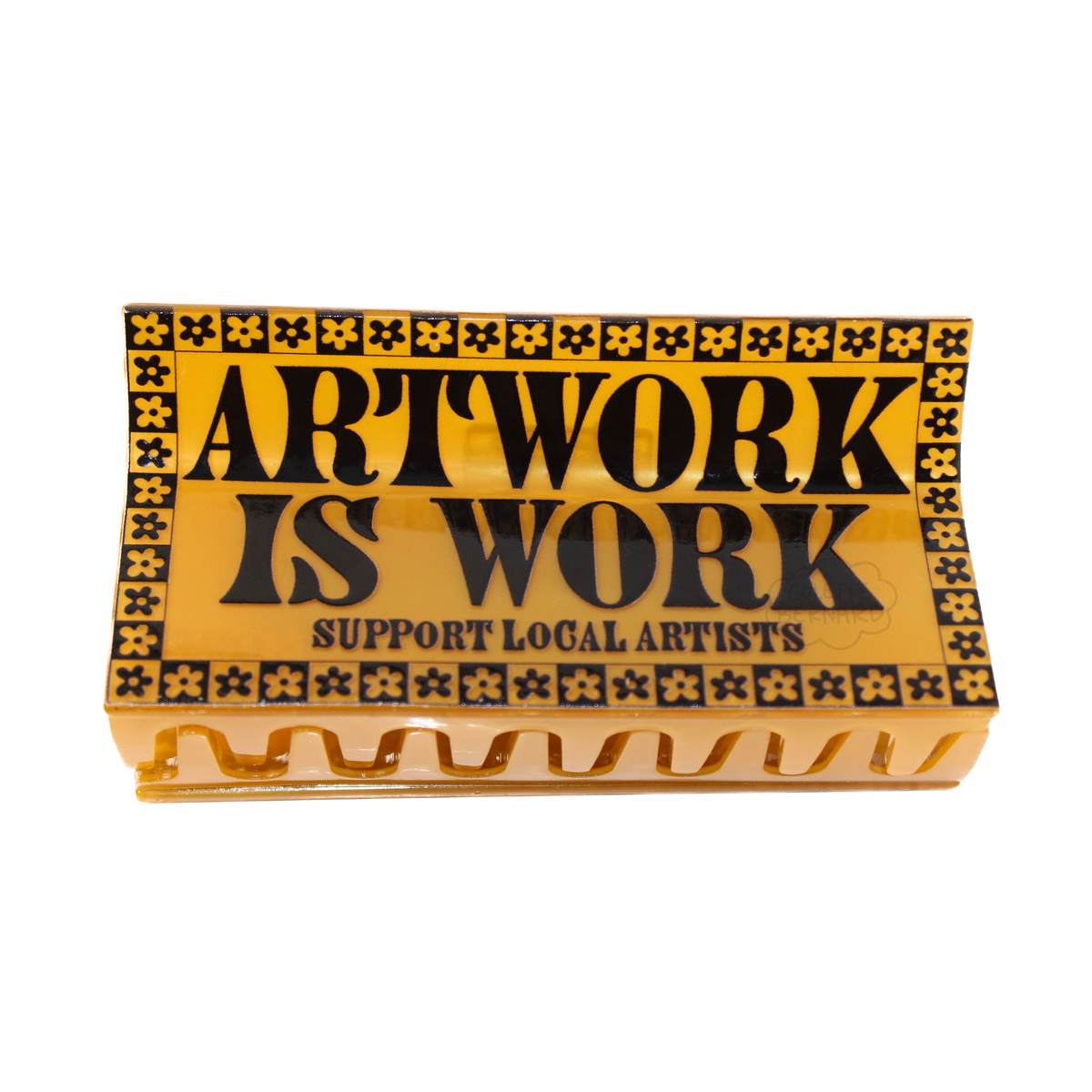 A hair claw with decorative border and text 'ARTWORK IS WORK SUPPORT LOCAL ARTISTS' on a white background