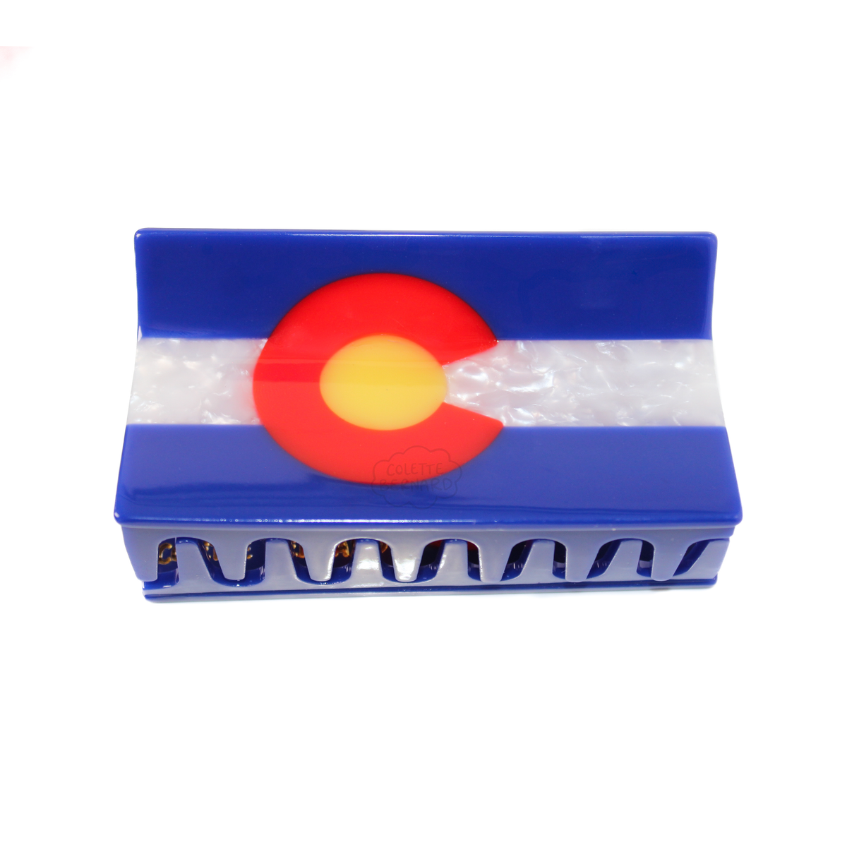 A hair claw styled like the Colorado state flag, featuring blue and white stripes with a red and yellow 'C' emblem, on a plain white background.
