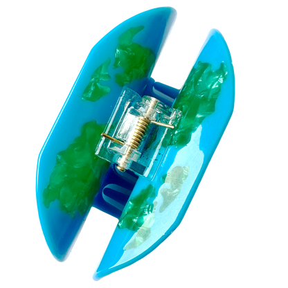 The World Map Hair Claw from above, showing the gold spring mechanism between the two blue and green marbled halves of the claw.