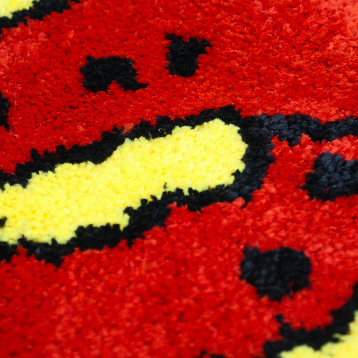 A close up of the Crawfish Claw Rug showing the fluffy red, yellow and black tufted texture.
