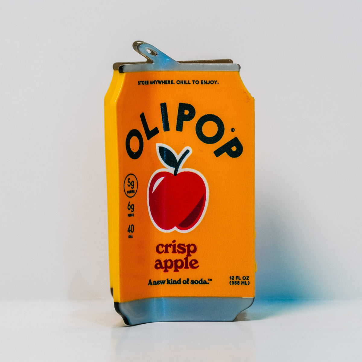 a hair claw designed to look like an Olipop Crisp Apple, featuring a red apple logo and OLIPOP branding, as well as the drink information