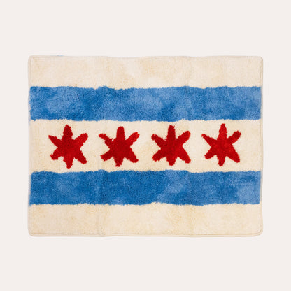 A rectangular plush rug featuring the Chicago city flag design, with two blue horizontal stripes and four red six-pointed stars on an off-white background, shown against a light cream backdrop.