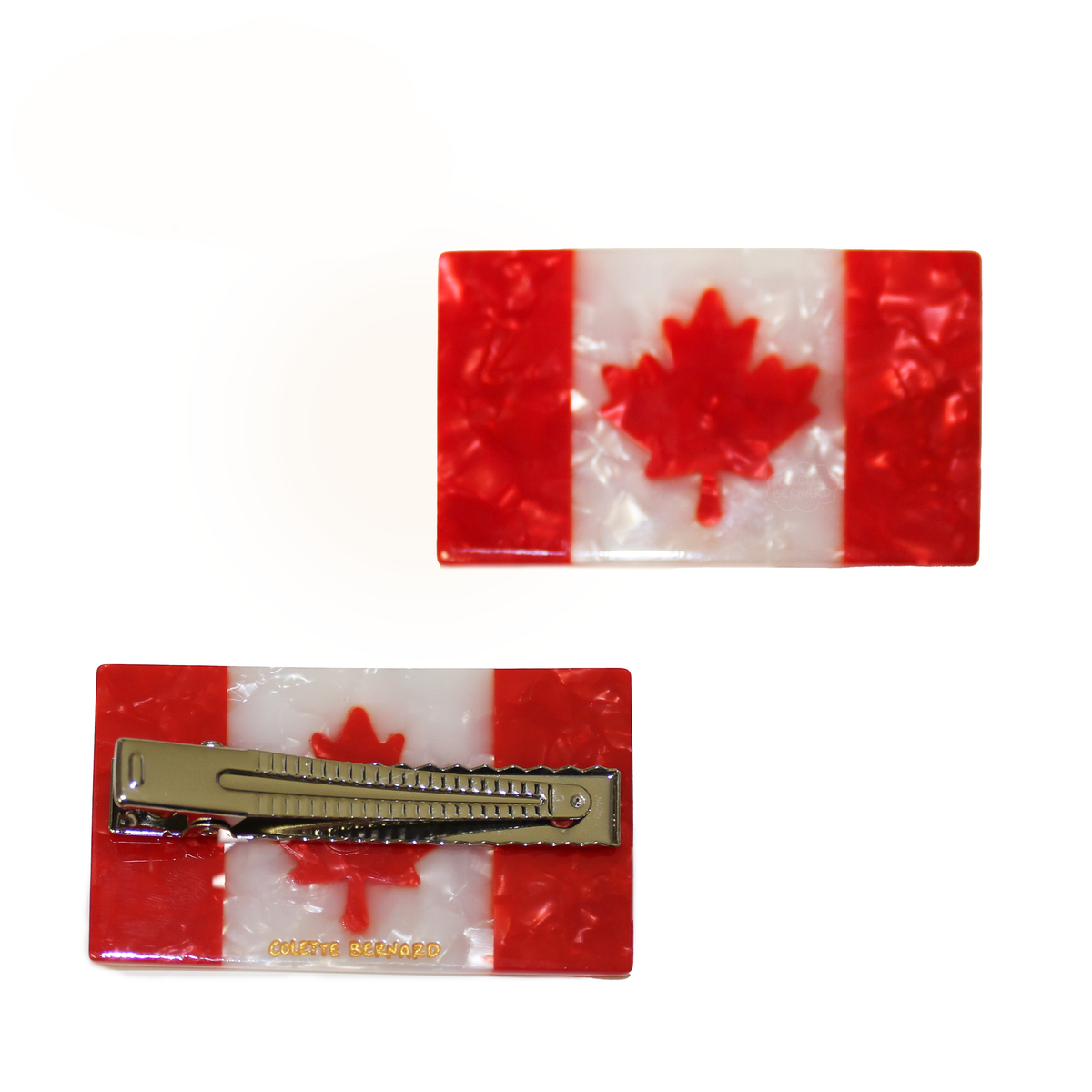 A hair clip designed to look like the canadian flag. There are two pictured on a white background. one is on its back showing the alligator clip mechanism and the gold Colette Bernard signature. The other clip is facing up, showing the flag design.