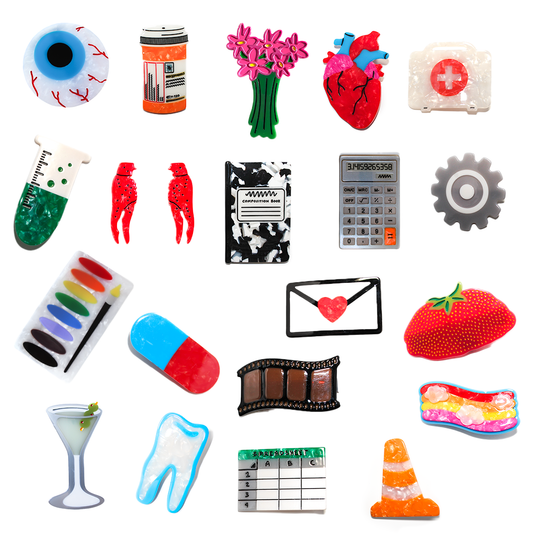 A grid of hair clip designs for the Mystery Hair Clip, including an eyeball, medicine bottle, anatomical heart, first aid kit, test tube, crawfish, calculator, gear, paint palette, pill capsule, martini, tooth and traffic cone.