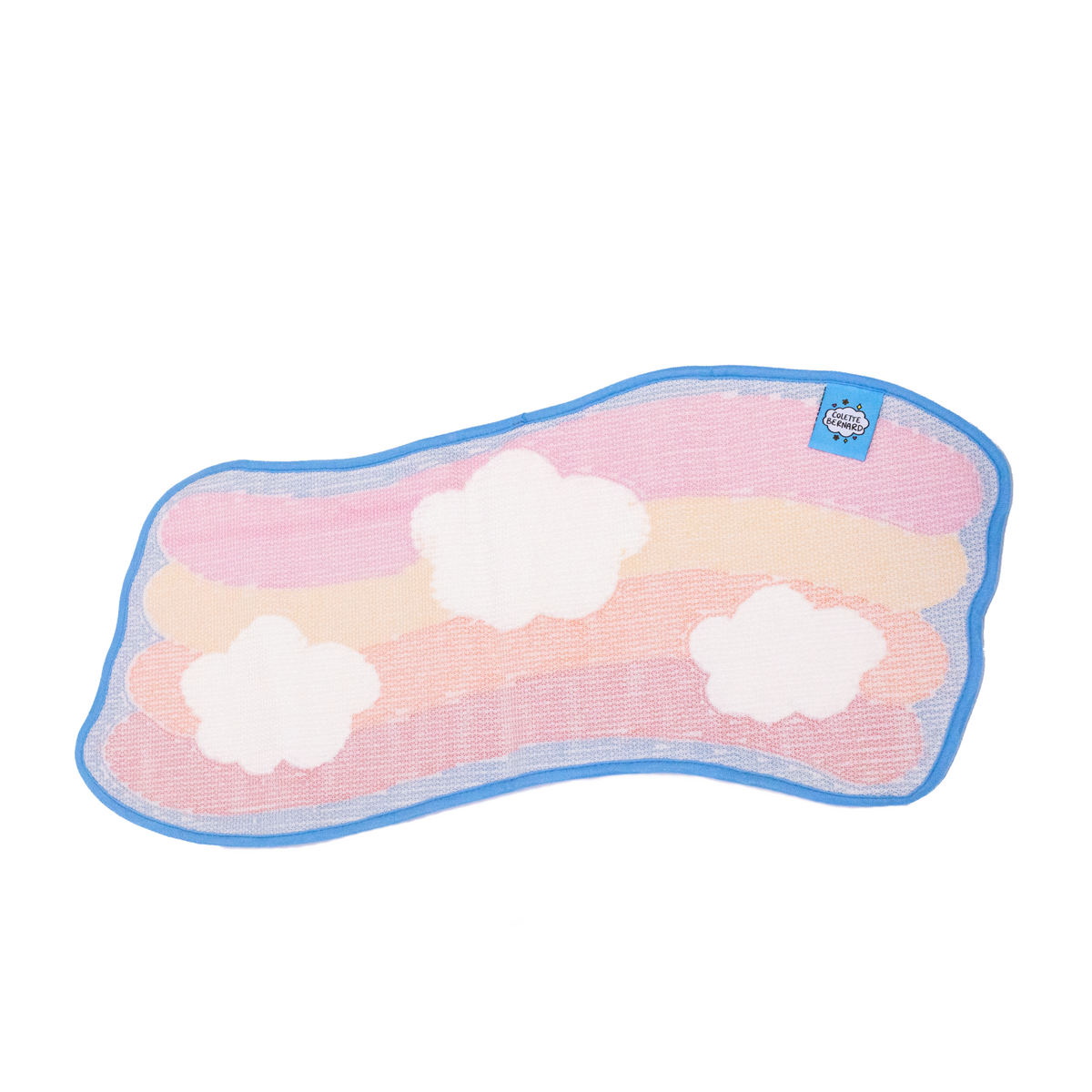 The back of the Daydream Rug on a white background, showing the faint rainbow and cloud pattern through the backing, the blue trim and a small Colette Bernard label.