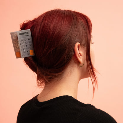 A person wearing the Calculator Hair Claw in their hair on a light pink background