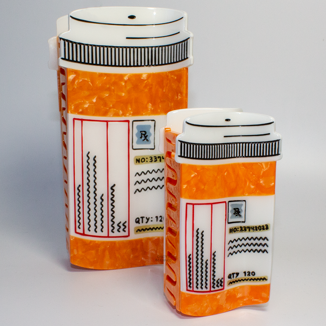 The Prescription Bottle Mega Claw next to the standard size Prescription Bottle Hair Claw to show the size difference, both orange with white caps and pharmacy labels reading 'Rx' and 'QTY: 120'.