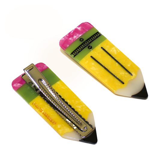Two Pencil Clips on a white background, one showing the front with a yellow pencil, pink eraser and green band, and one flipped over showing the silver alligator clip and the gold Colette Bernard logo.