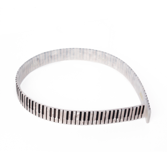 A white pearl headband printed with black and white piano keys, shown on a plain white background.