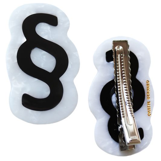 The Section Sign Hair Clip shown front and back on a white background, a black section symbol on white marbled acetate, with the silver alligator clip and gold Colette Bernard logo on the back.