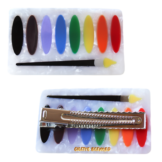Two Watercolor Palette Hair Clips on a white background, one showing the pearly white palette with eight rainbow paint ovals and a paintbrush, and one flipped to show the silver alligator clip and gold Colette Bernard logo.